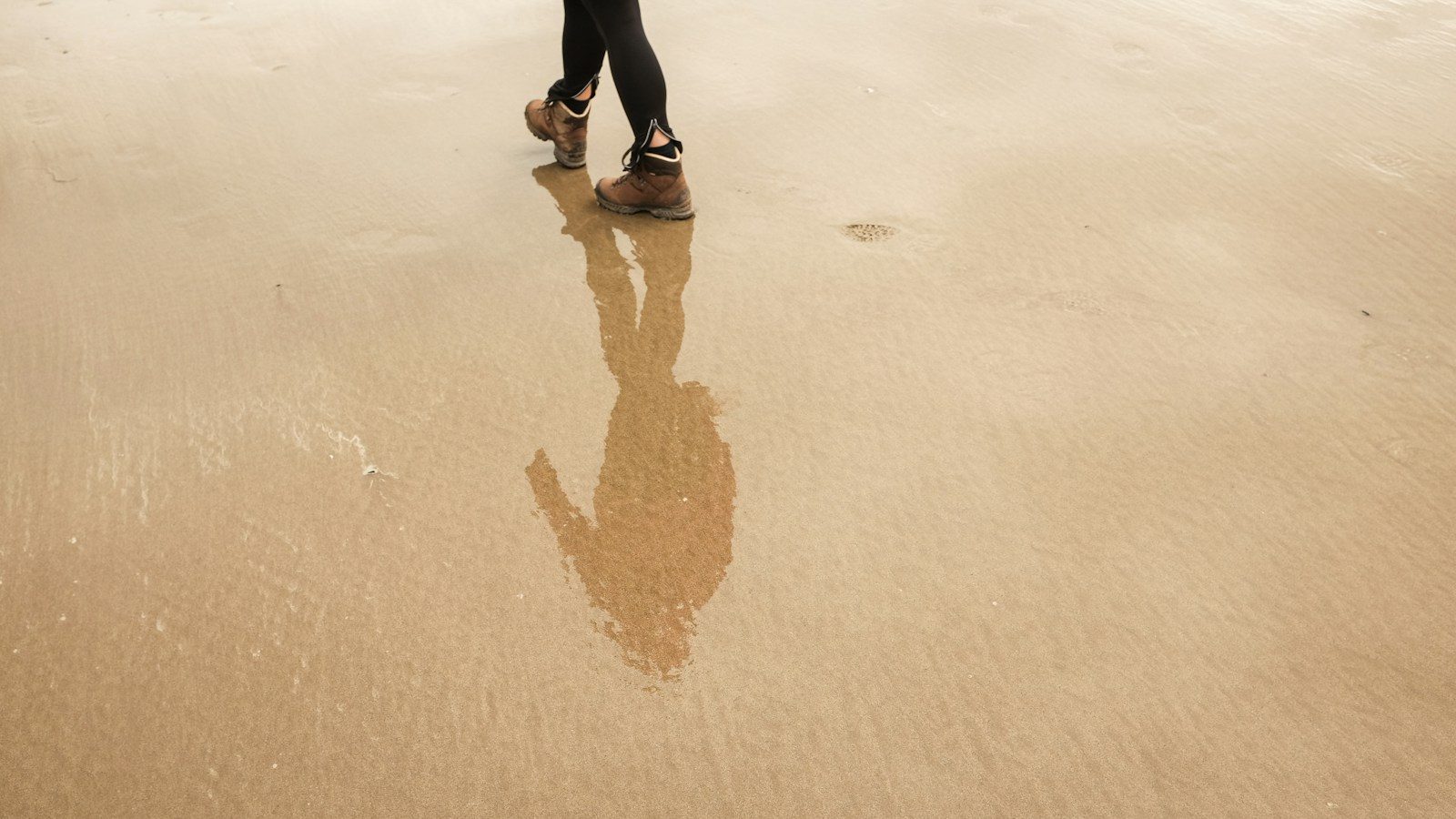 reflection of man on wet sand